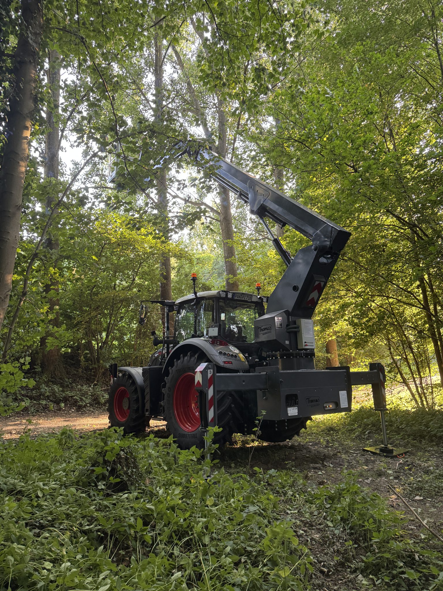 Grijze 240 PTO hoogwerker van Thomas & Ufkes op Fendt van achteren gezien in bos