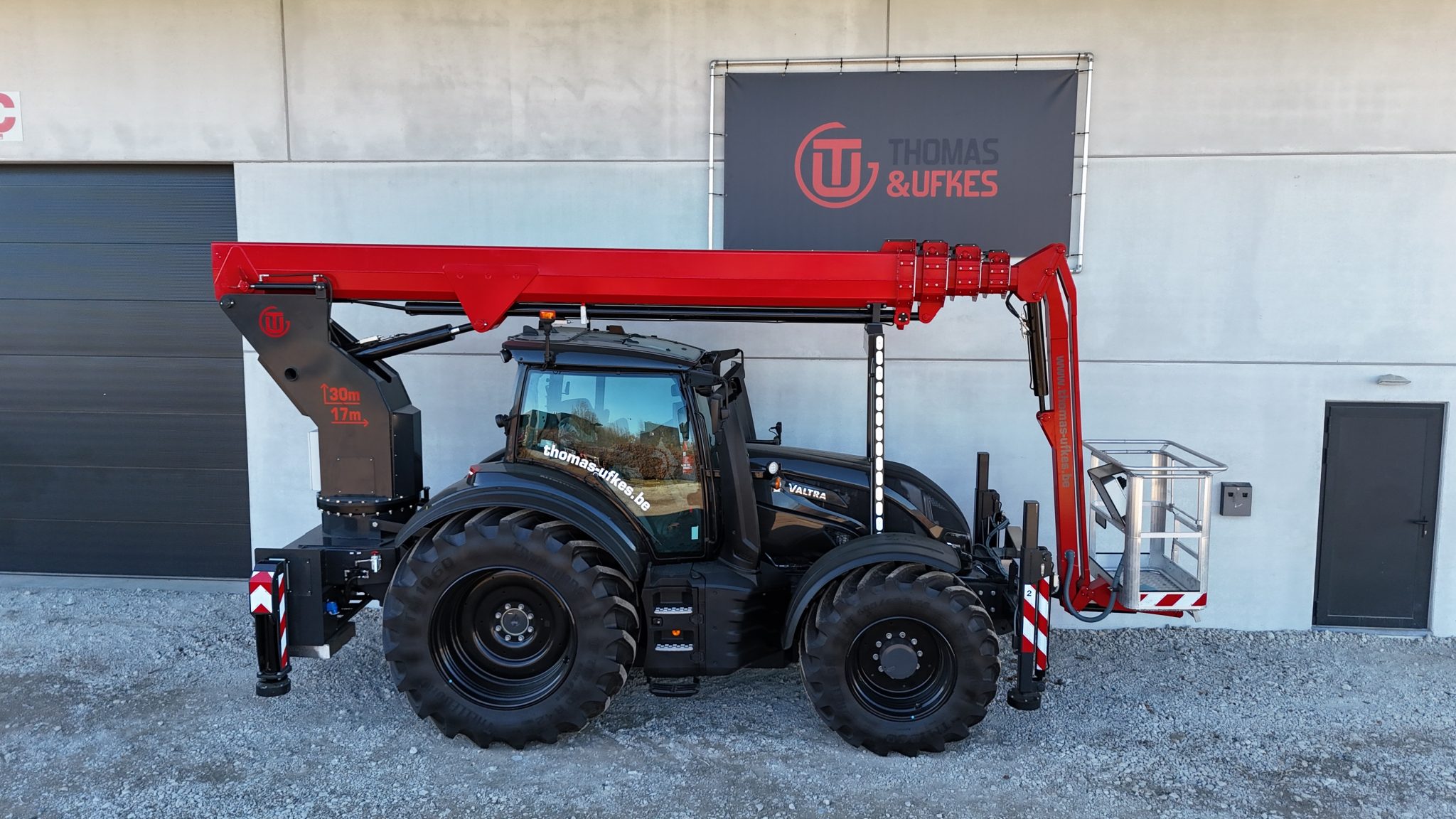 Thomas & Ufkes 300 PTO rode hoogwerker op zwarte Valtra tractor zij-aanzicht voor Thomas & Ufkes depot – 17m tot 30m werkhoogte